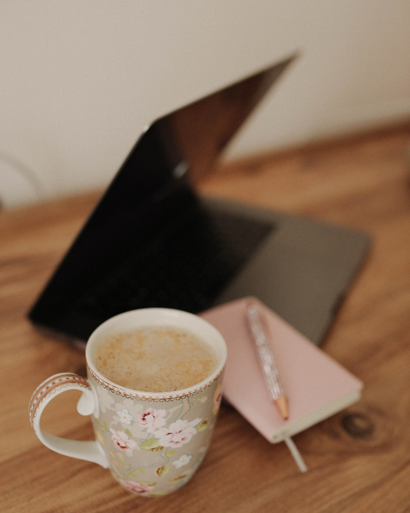 Laptop, notebook and a cup of tea set up for an online therapy session at home