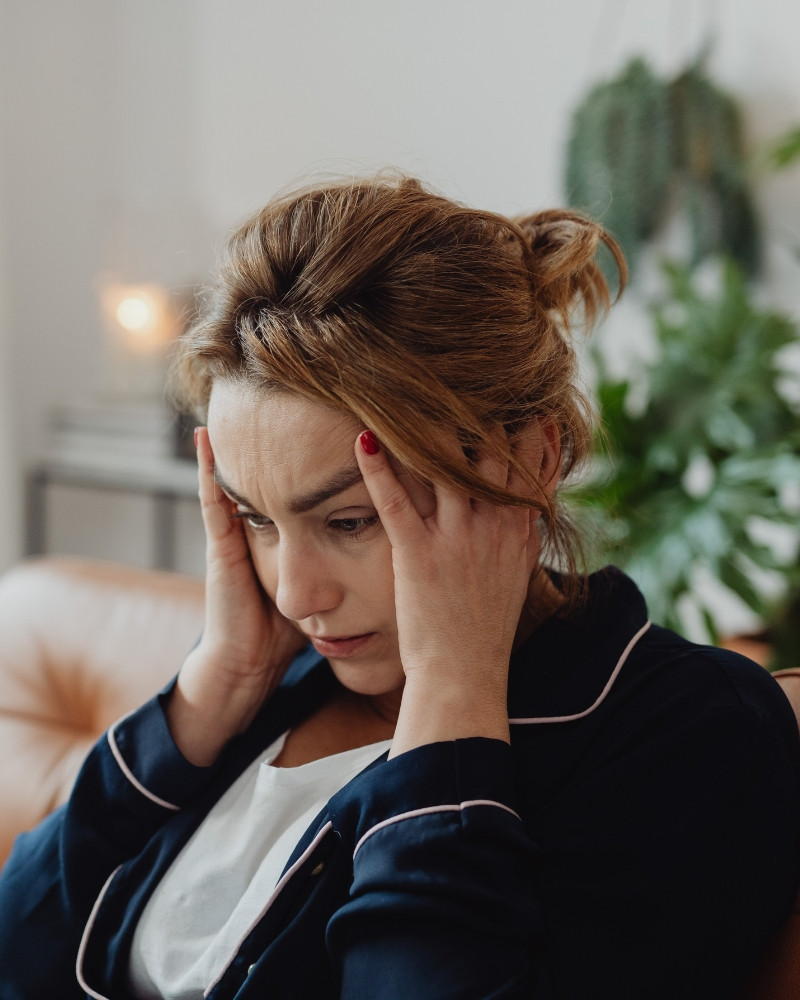 Woman holding her head, feeling anxious and worried about her health
